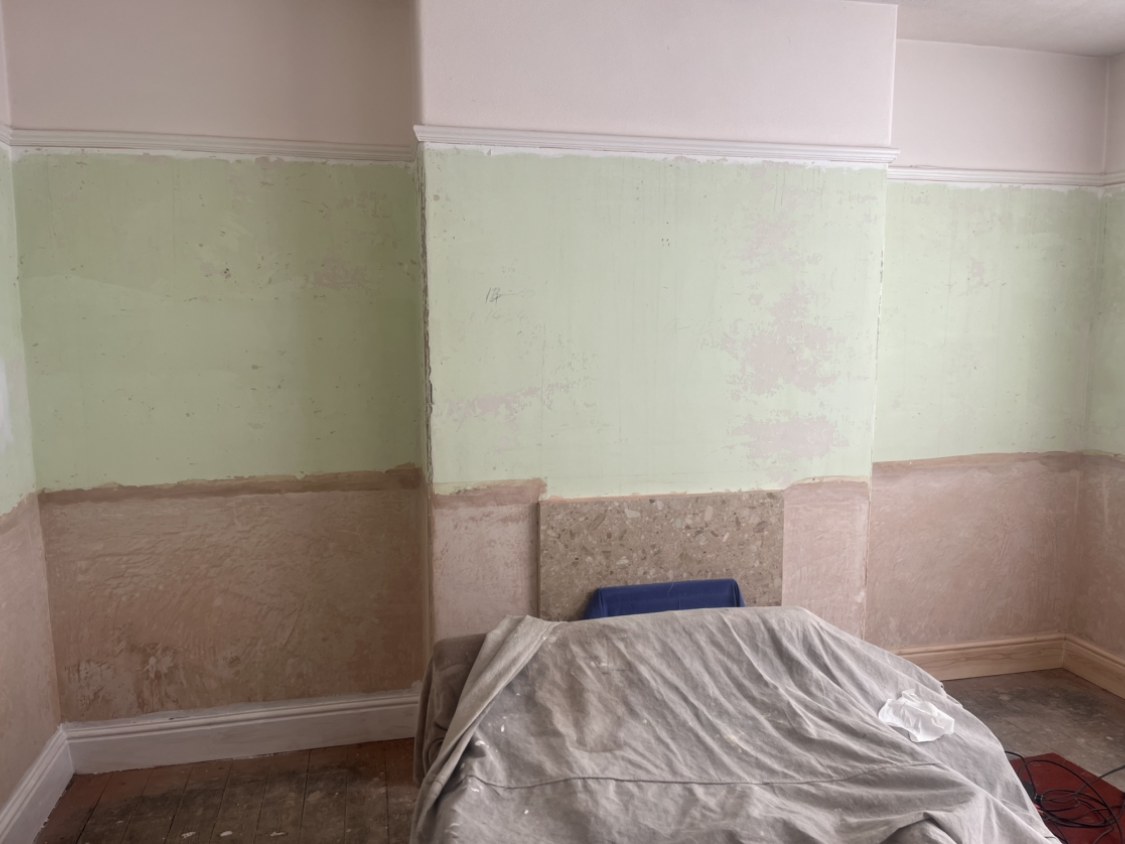 Burnley living room walls stripped back to bare plaster showing cracking and damage before repair