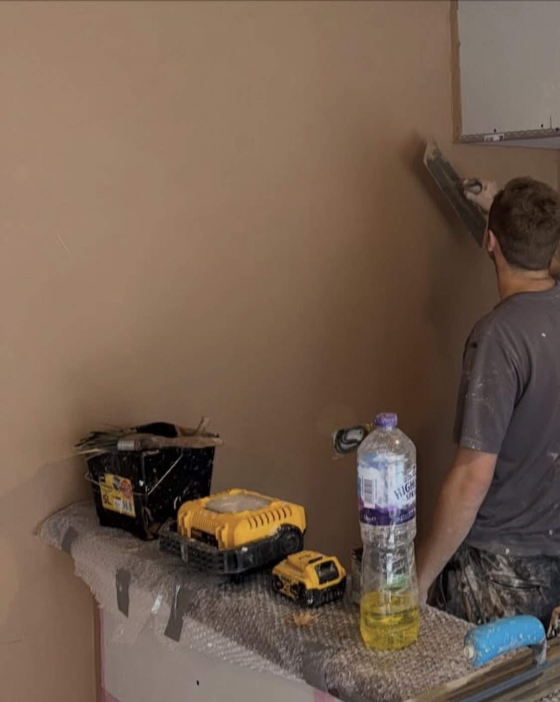 Plasterer applying a finish coat to a wall on a Lancashire job